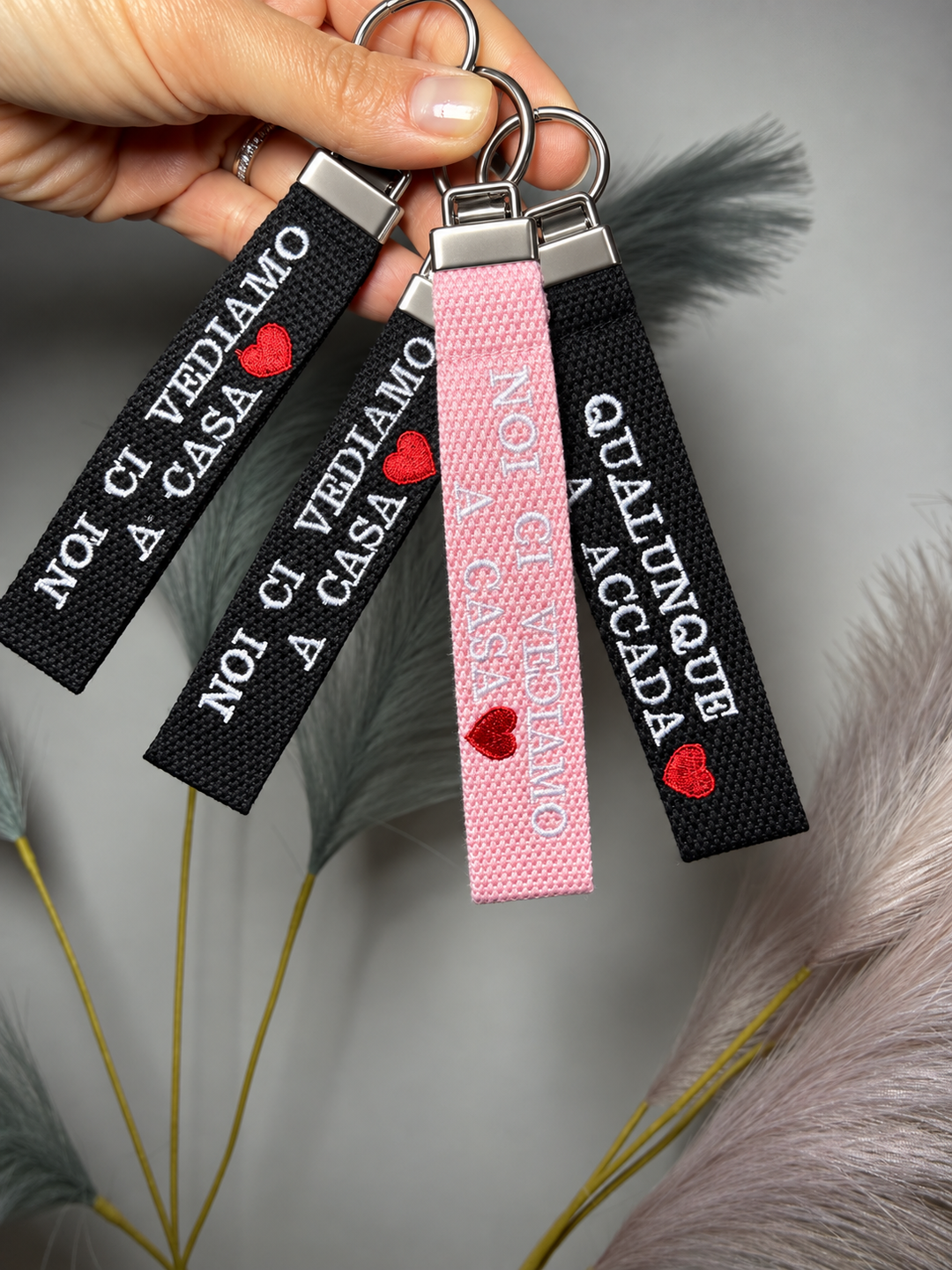 Portachiavi in tela nera e rosa con frase ricamata personalizzata tenuti in mano
