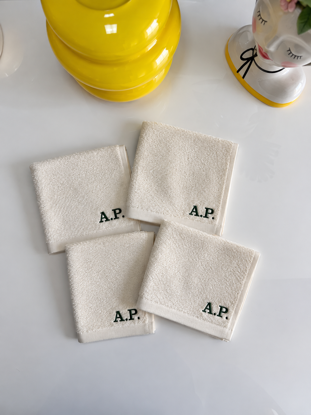 Set di quattro asciugamani colorate in cotone bianco con monogramma A.P., dimensioni 30x30 cm, ideali per cura quotidiana, in ambiente bagno elegante