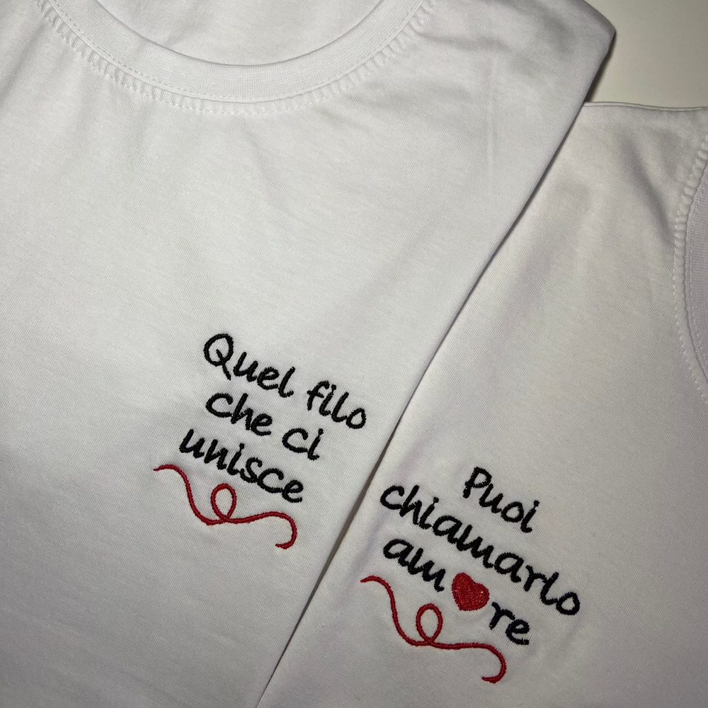 T-shirt  personalizzabile in cotone bianco con scritte ricamate 'Quel filo che ci unisce' e 'Puoi chiamarlo amore', stile unico e originale.