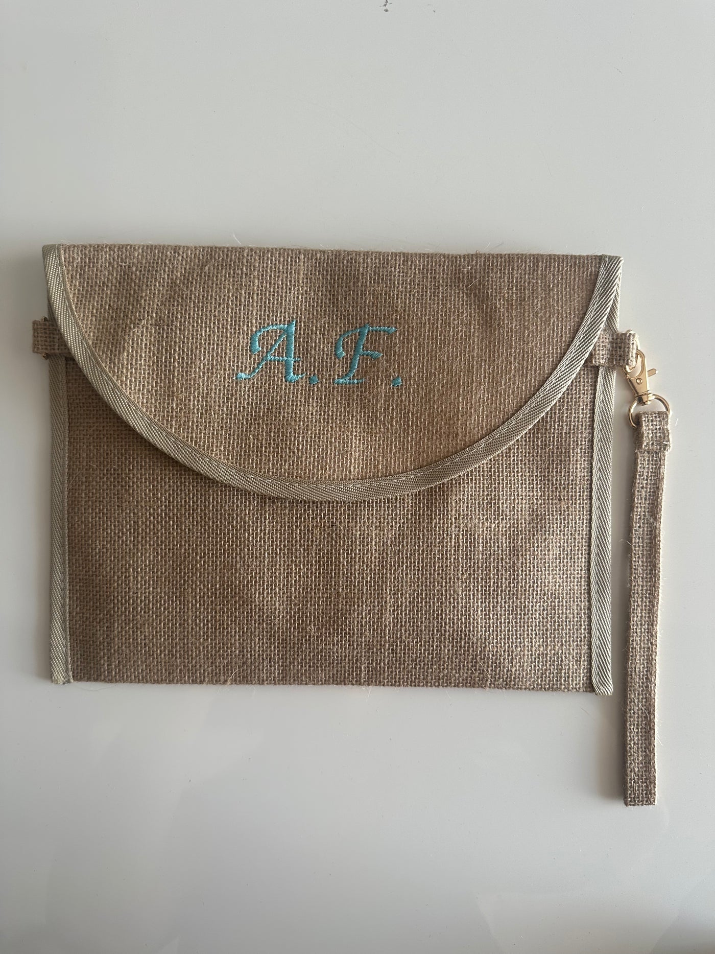 Pochette in juta personalizzata con iniziali, chiusura a patta e cinturino laterale, ideale come borsa elegante e sostenibile.