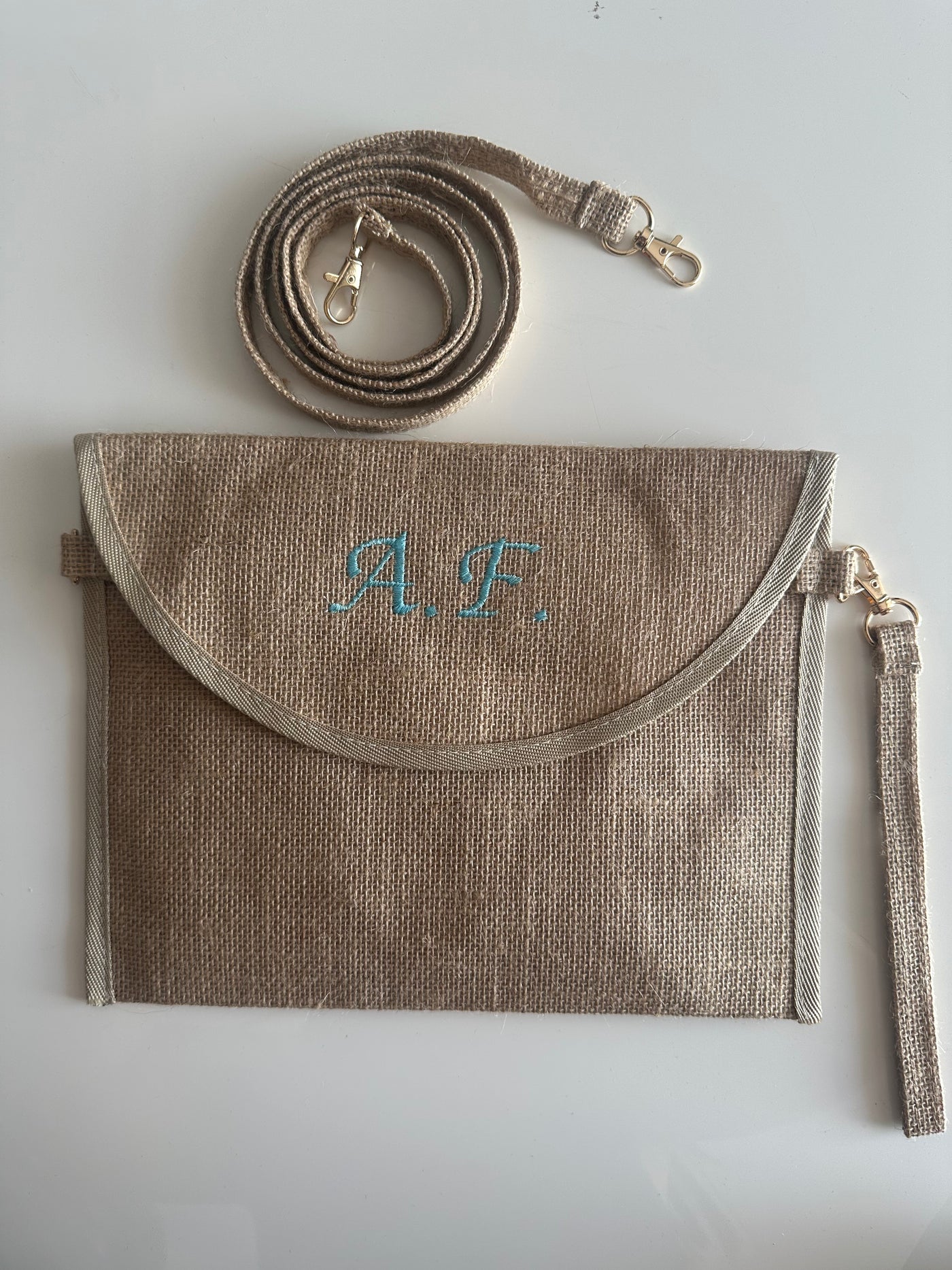Pochette in juta personalizzata con iniziali, dotata di tracolla e cinturino removibili. Elegante borsa clutch ideale per ogni occasione.