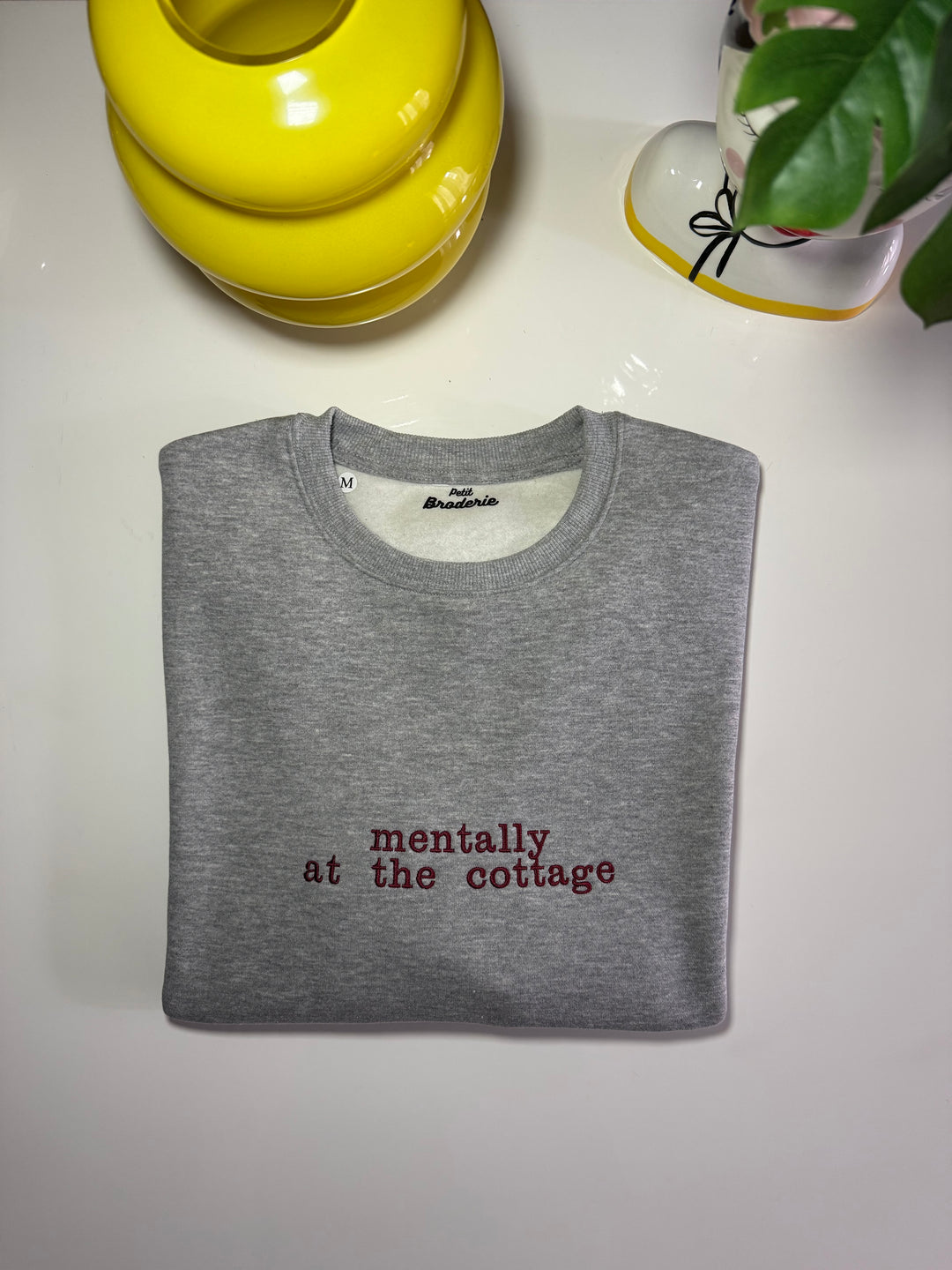 Felpa girocollo grigia con scritta ricamata bordeaux "mentally at the cottage" al centro