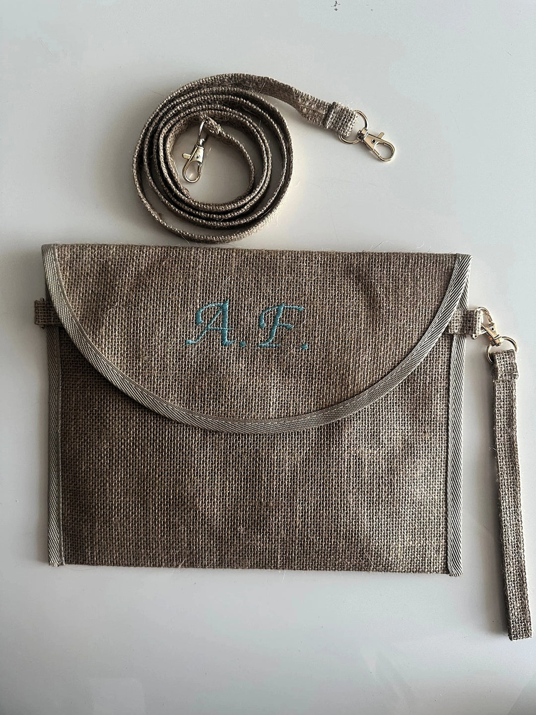 Pochette in juta personalizzata con iniziali, dotata di tracolla e cinturino removibili. Elegante borsa clutch ideale per ogni occasione.