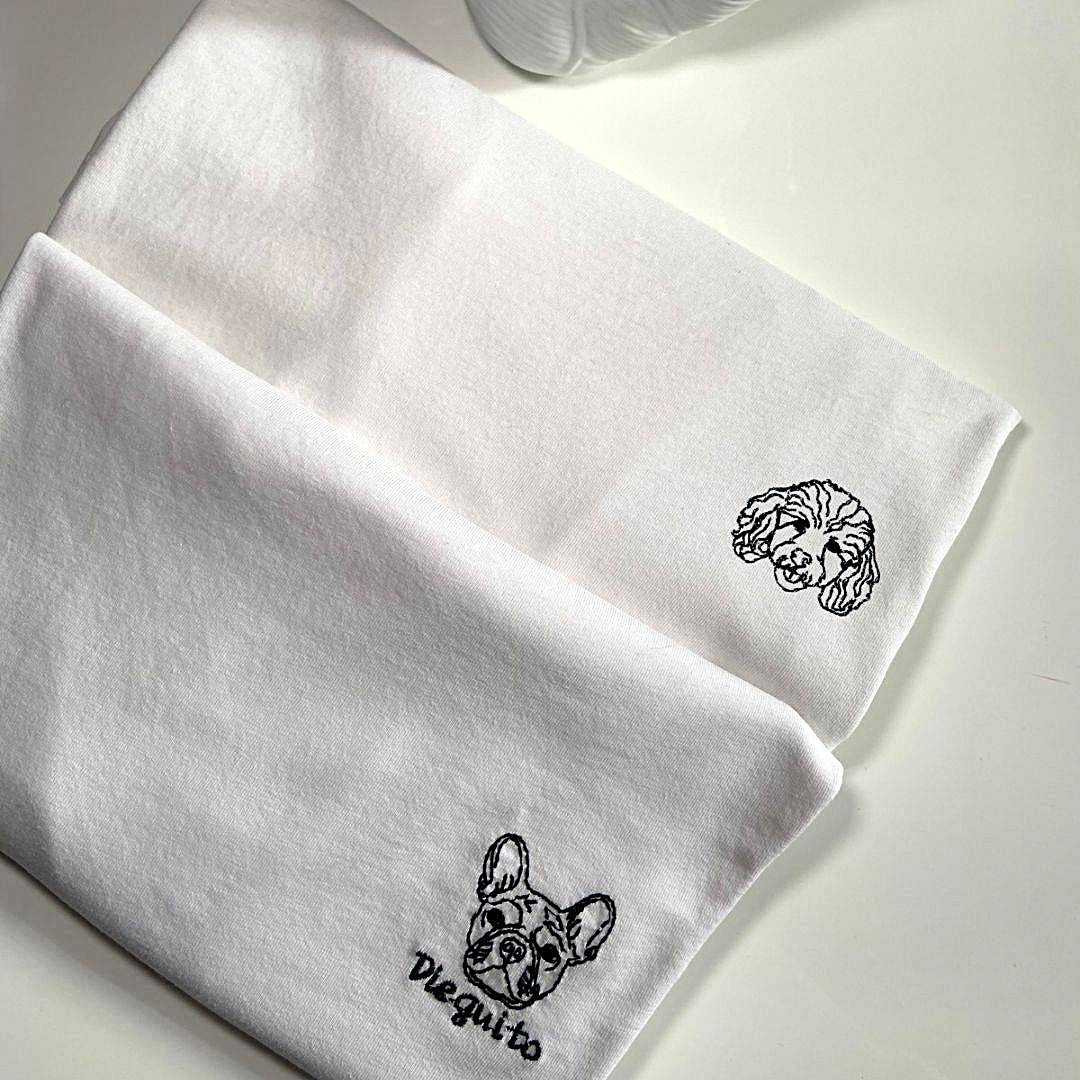 Dettaglio del ricamo di un cane con nome su t-shirt bianca