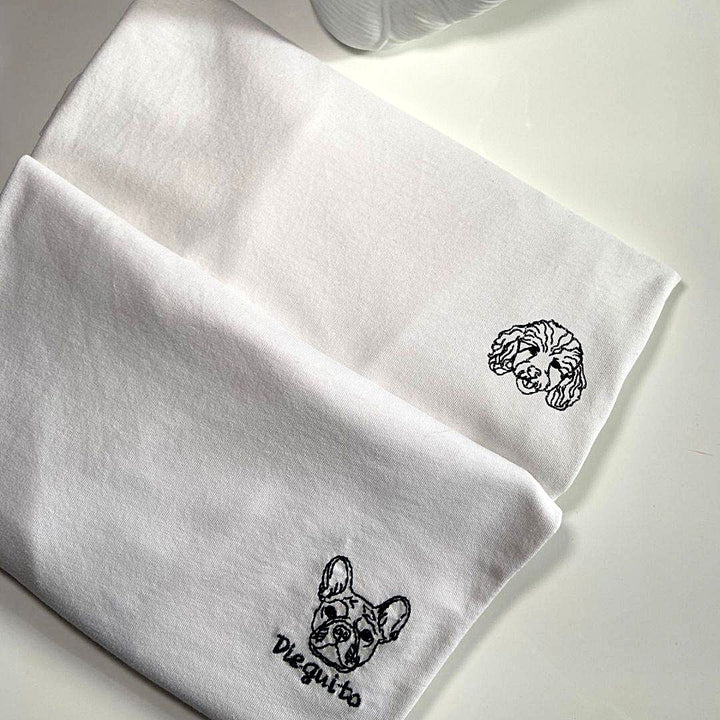 Dettaglio del ricamo di un cane con nome su t-shirt bianca